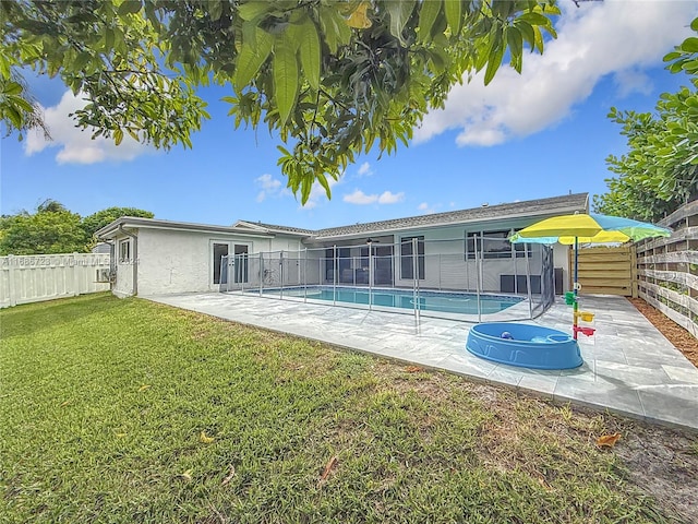 back of house featuring a lawn, a patio, and a fenced in pool