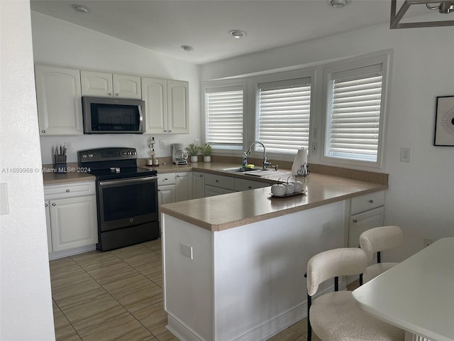 kitchen featuring white cabinets, lofted ceiling, sink, and appliances with stainless steel finishes