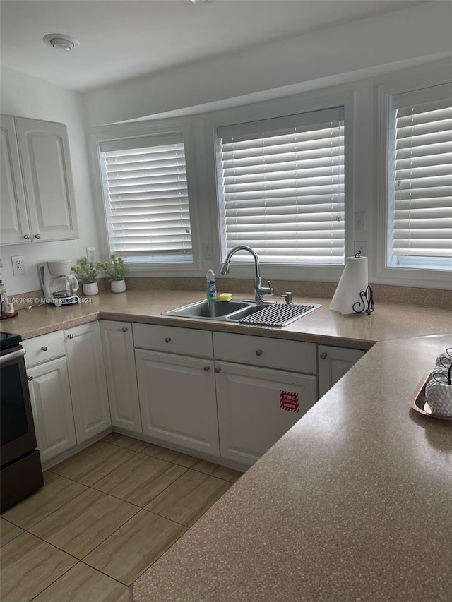 kitchen with white cabinetry, sink, and stainless steel electric stove