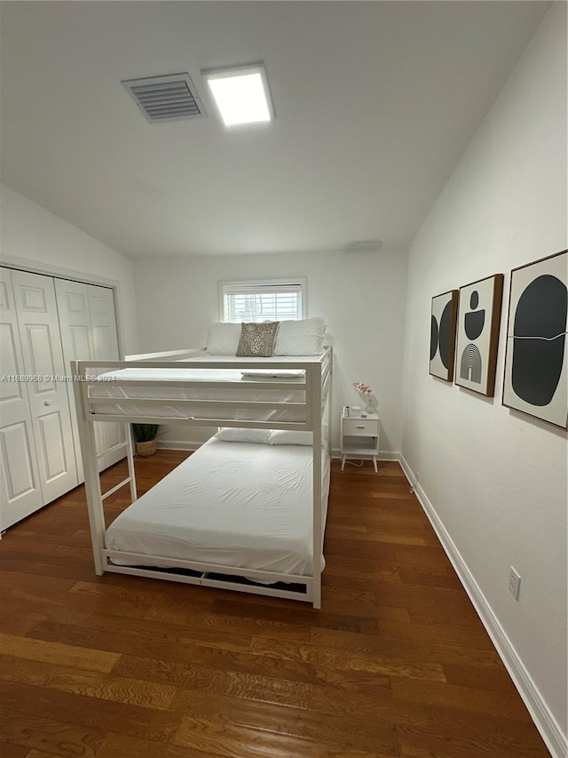 bedroom with dark hardwood / wood-style flooring, lofted ceiling, and a closet