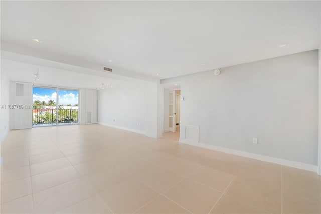 tiled spare room featuring a notable chandelier