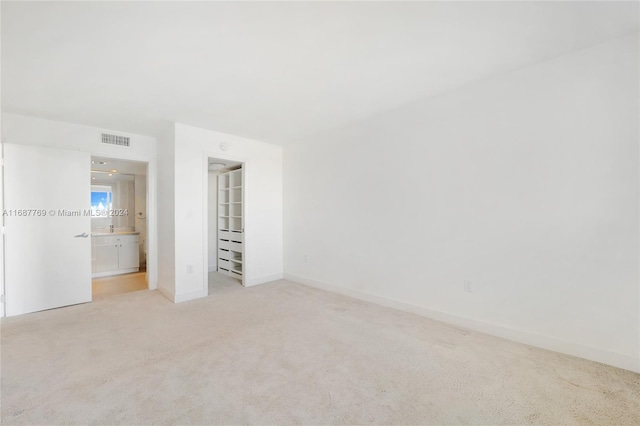 unfurnished bedroom featuring ensuite bathroom and light carpet