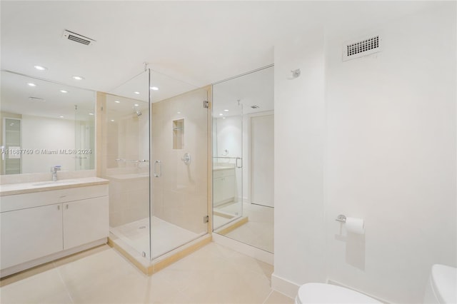 bathroom featuring walk in shower, vanity, toilet, and tile patterned floors