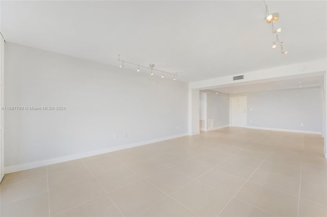 tiled empty room featuring track lighting