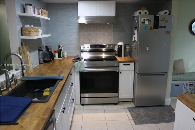 kitchen with stainless steel appliances, light tile patterned floors, wood counters, sink, and white cabinets