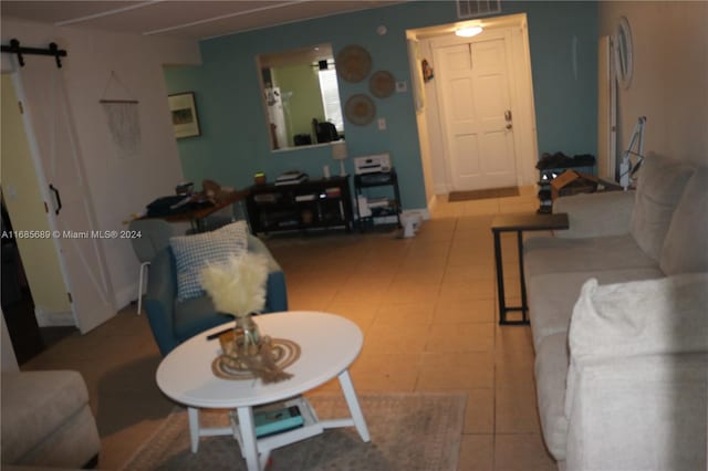 living room with a barn door and light tile patterned floors