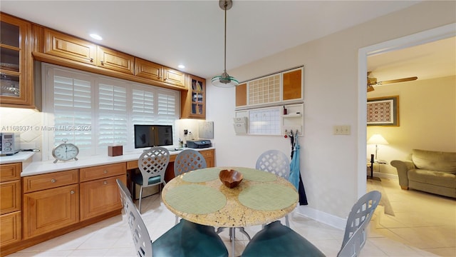 tiled dining room featuring built in desk and ceiling fan