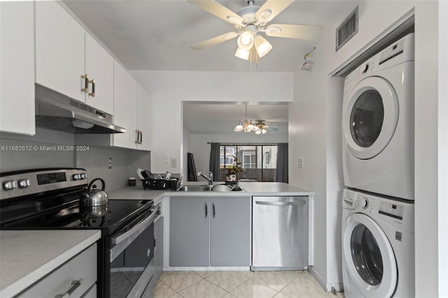 kitchen featuring sink, light tile patterned floors, white cabinetry, appliances with stainless steel finishes, and stacked washer / drying machine