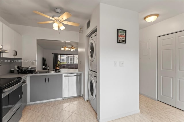 kitchen with ceiling fan with notable chandelier, appliances with stainless steel finishes, sink, and stacked washer / drying machine