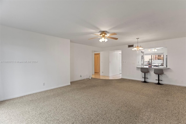 unfurnished living room featuring ceiling fan with notable chandelier and carpet floors