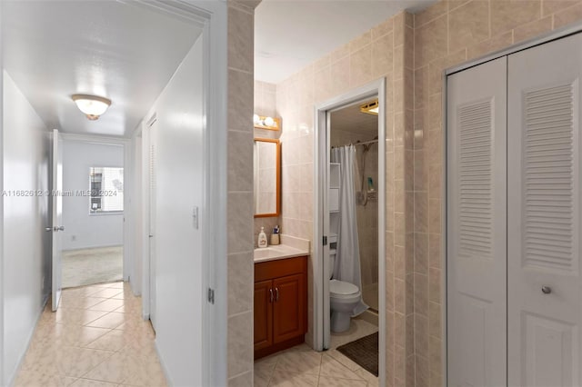 bathroom with tile walls, vanity, toilet, and walk in shower