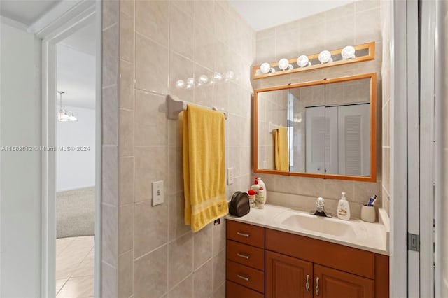 bathroom with vanity, tile walls, tile patterned flooring, and a notable chandelier