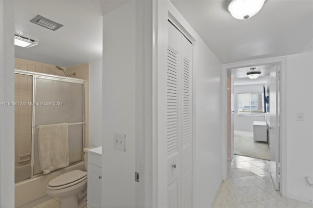 full bathroom featuring toilet, vanity, bath / shower combo with glass door, and tile patterned flooring