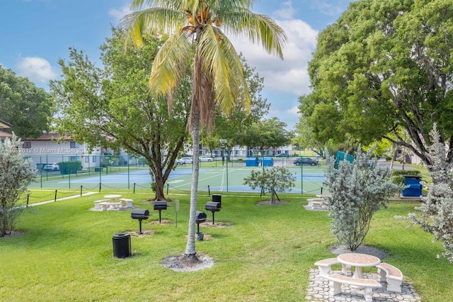 view of community featuring tennis court and a yard