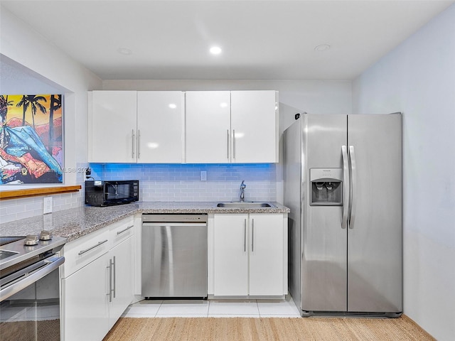 kitchen featuring light stone countertops, appliances with stainless steel finishes, white cabinetry, and sink