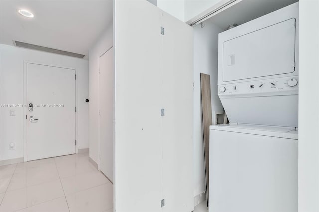 washroom with light tile patterned flooring and stacked washer and dryer