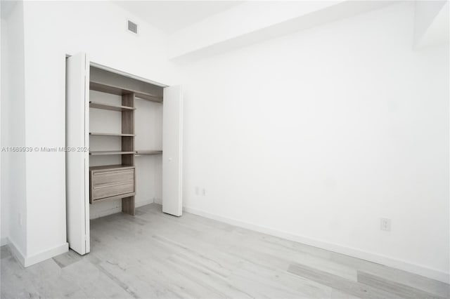 unfurnished bedroom featuring light hardwood / wood-style flooring and a closet