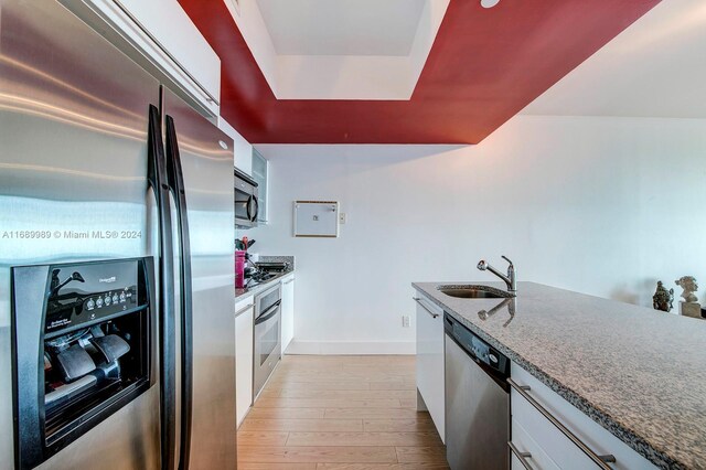 888 Biscayne Blvd Unit 4007, Miami, FL 33132 - kitchen featuring stainless steel appliances, a sink, light wood-type flooring, white cabinets, and dark stone counters