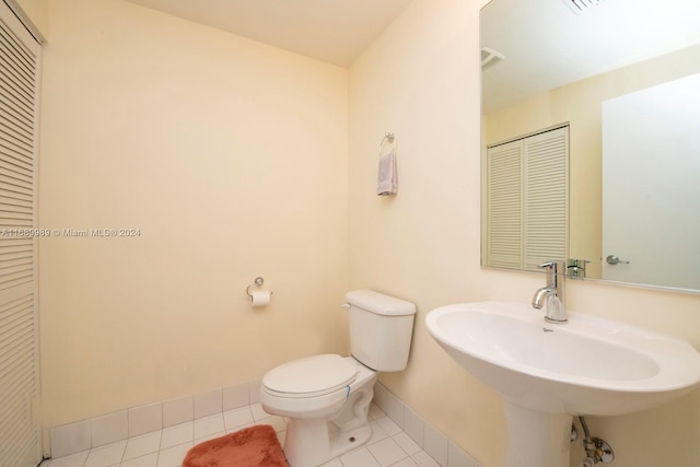 bathroom with toilet, sink, and tile patterned floors