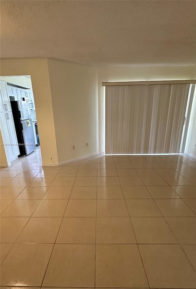 empty room with light tile patterned floors and a textured ceiling