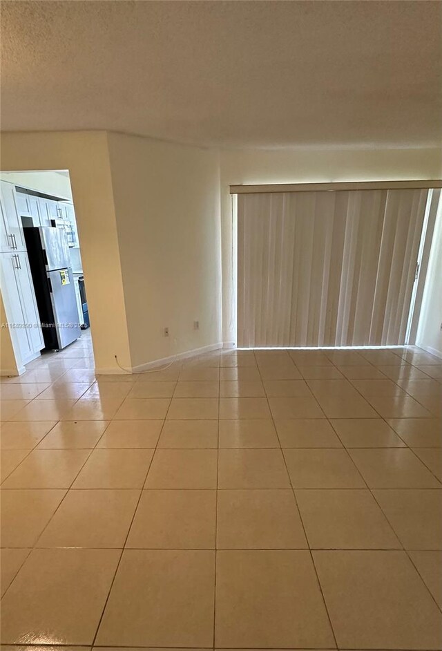 spare room featuring light tile patterned floors and a textured ceiling