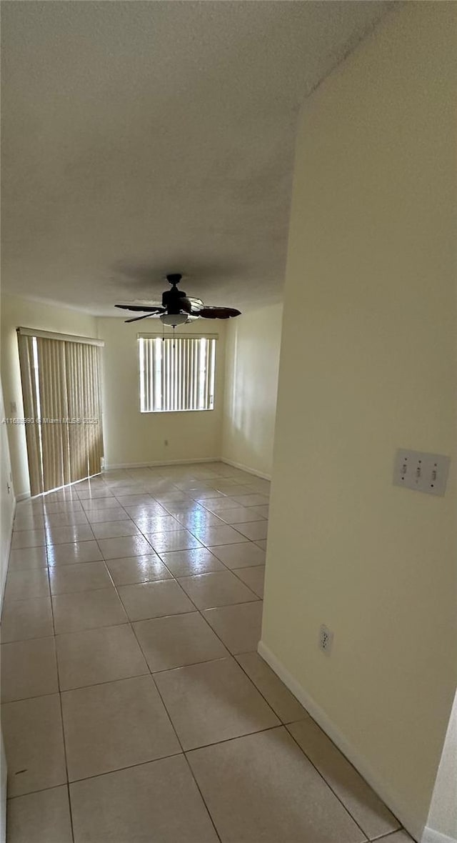 tiled empty room with ceiling fan and a textured ceiling