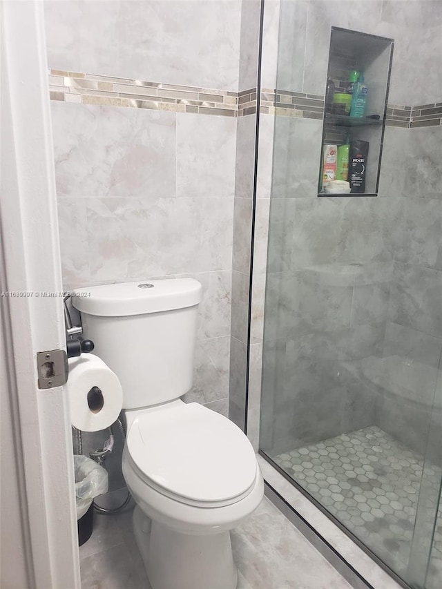 bathroom featuring tile walls, an enclosed shower, and toilet