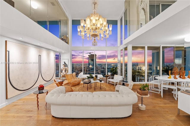 living room featuring a high ceiling, a chandelier, light hardwood / wood-style flooring, and a wall of windows