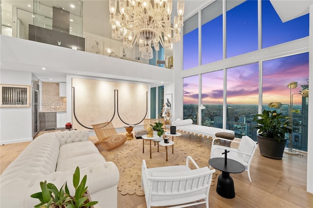 living room featuring a towering ceiling, light hardwood / wood-style flooring, and a chandelier