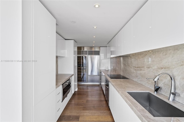 kitchen featuring black electric cooktop, sink, oven, white cabinets, and dark hardwood / wood-style flooring