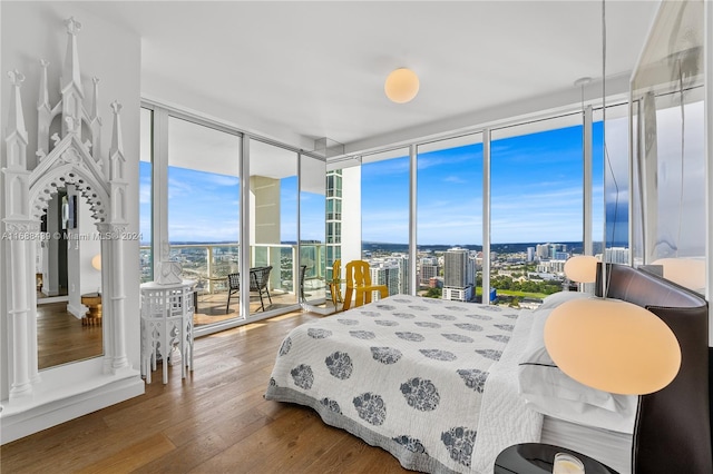 bedroom featuring access to outside, expansive windows, and wood-type flooring