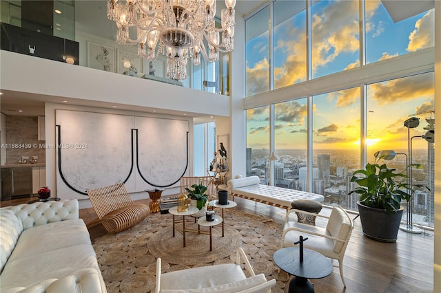 living room featuring a towering ceiling, wood-type flooring, and a chandelier