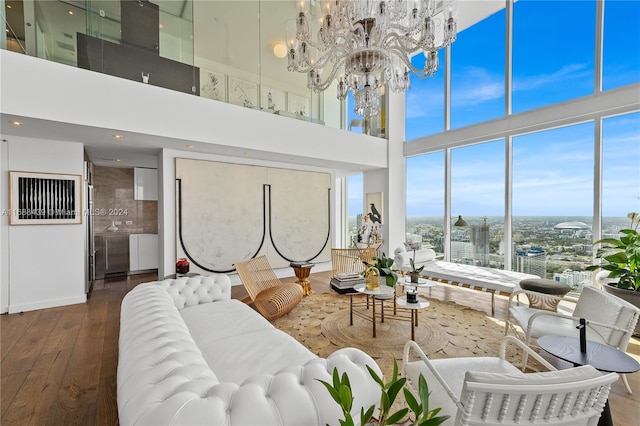 living room with a towering ceiling, a notable chandelier, and dark wood-type flooring