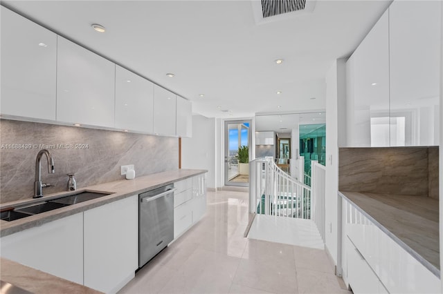 kitchen with white cabinetry, stainless steel dishwasher, tasteful backsplash, and sink