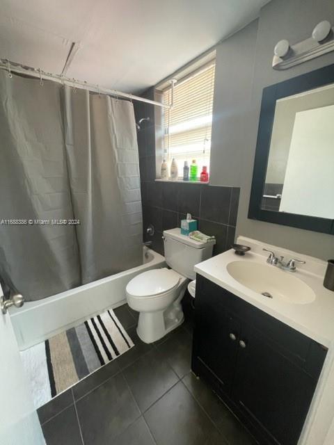 1200 Euclid Ave Unit 109, Miami Beach, FL 33139 - full bathroom featuring shower / bath combo with shower curtain, tile patterned floors, toilet, vanity, and tile walls