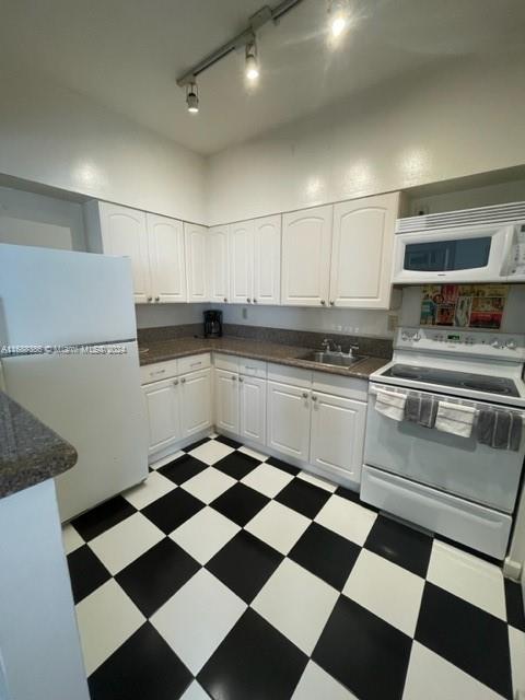 1200 Euclid Ave Unit 109, Miami Beach, FL 33139 - kitchen with white appliances, dark countertops, light flooring, and rail lighting