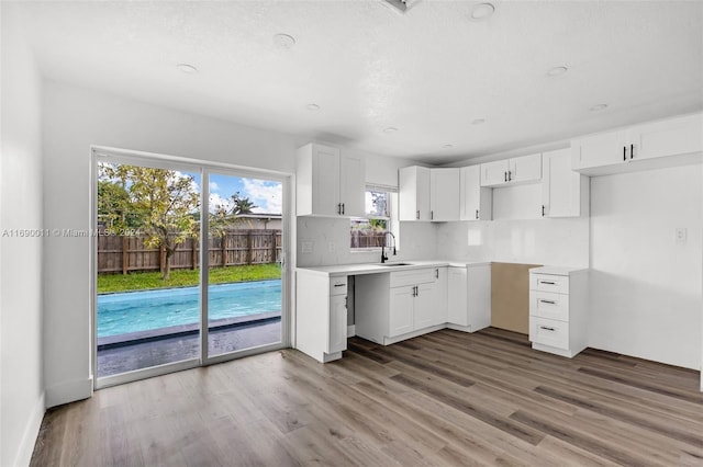 kitchen with white cabinets, hardwood / wood-style flooring, sink, and backsplash