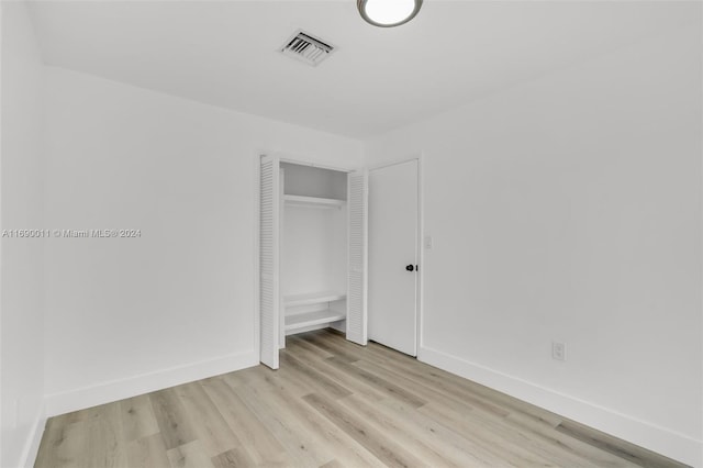 unfurnished bedroom with light wood-type flooring and a closet