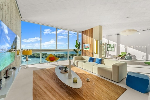 living room with concrete flooring, a water view, and a wall of windows