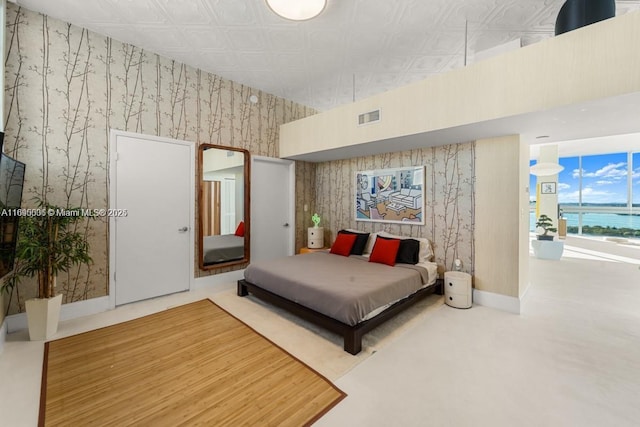 bedroom with a water view, an ornate ceiling, visible vents, baseboards, and wallpapered walls