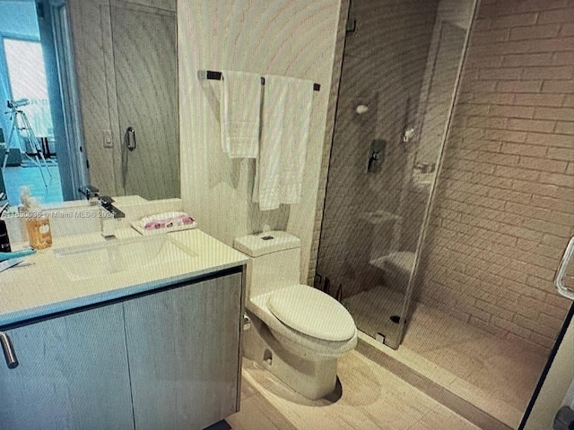 bathroom with a shower with shower door, vanity, and toilet