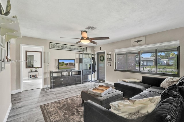 living room featuring baseboards, wood finished floors, visible vents, and ceiling fan