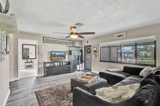 living room with a textured ceiling, hardwood / wood-style flooring, and ceiling fan