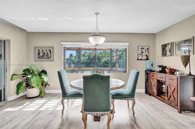 dining area featuring a textured ceiling, a notable chandelier, and light hardwood / wood-style floors