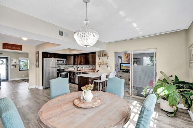 dining space with a chandelier and light hardwood / wood-style flooring