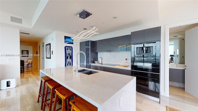 kitchen featuring light hardwood / wood-style floors, a center island with sink, sink, and a breakfast bar