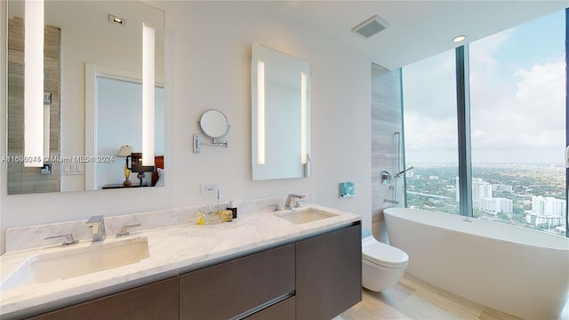 bathroom with plenty of natural light, a washtub, vanity, and wood-type flooring