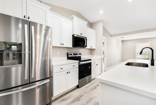 kitchen featuring white cabinets, stainless steel appliances, lofted ceiling, and sink