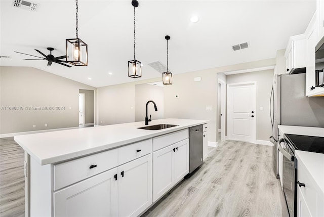 kitchen with a center island with sink, white cabinetry, pendant lighting, sink, and vaulted ceiling