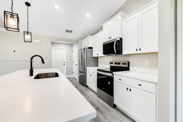 kitchen featuring stainless steel appliances, pendant lighting, sink, white cabinetry, and light wood-type flooring